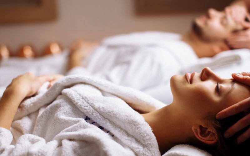 happy young beautiful couple enjoying head massage at the spa