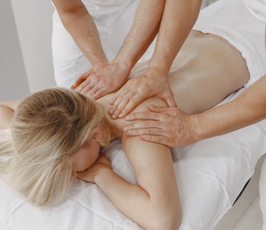 The massage with four hands. Concept of healthcare and female beauty. Two masseuses make a double  massage of a girl. Woman in a spa salon.