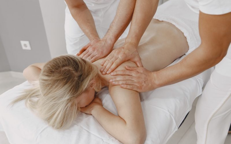 The massage with four hands. Concept of healthcare and female beauty. Two masseuses make a double  massage of a girl. Woman in a spa salon.